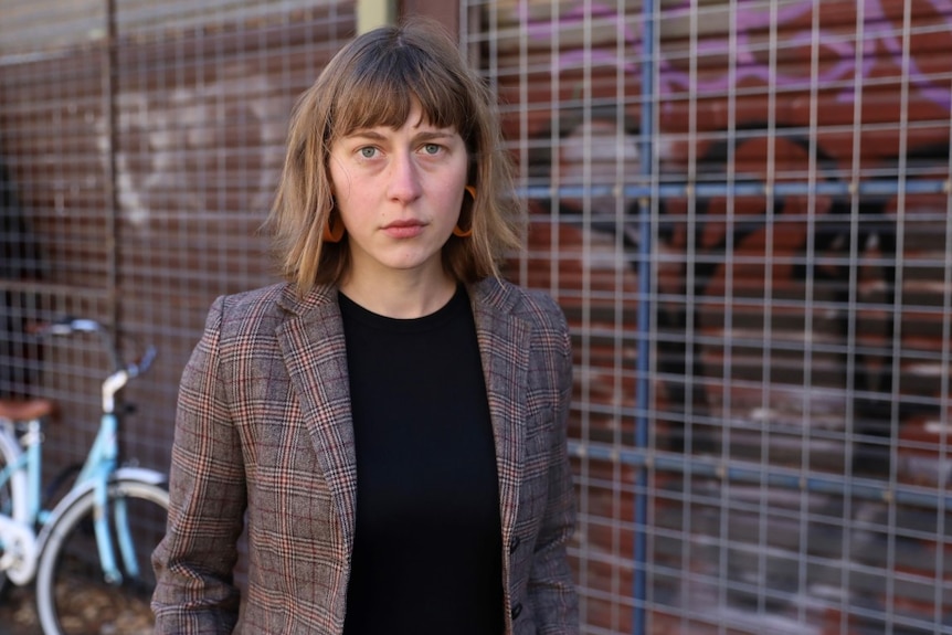 A woman stands in an alleyway