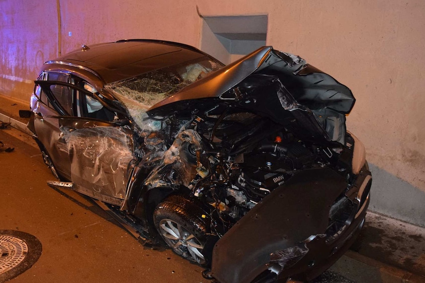a car with its front smashed in shown in a tunnel