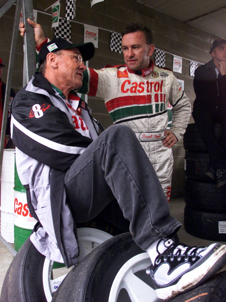 Two racing drivers talk to each other in the pits after the top-10 qualification before a big race.