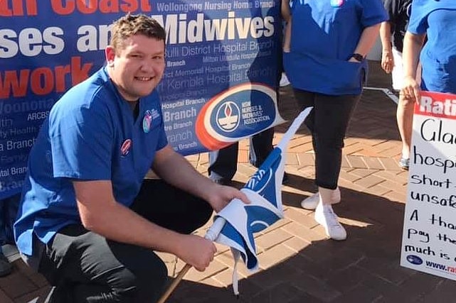 a man squatting in front of a banner holding a flag