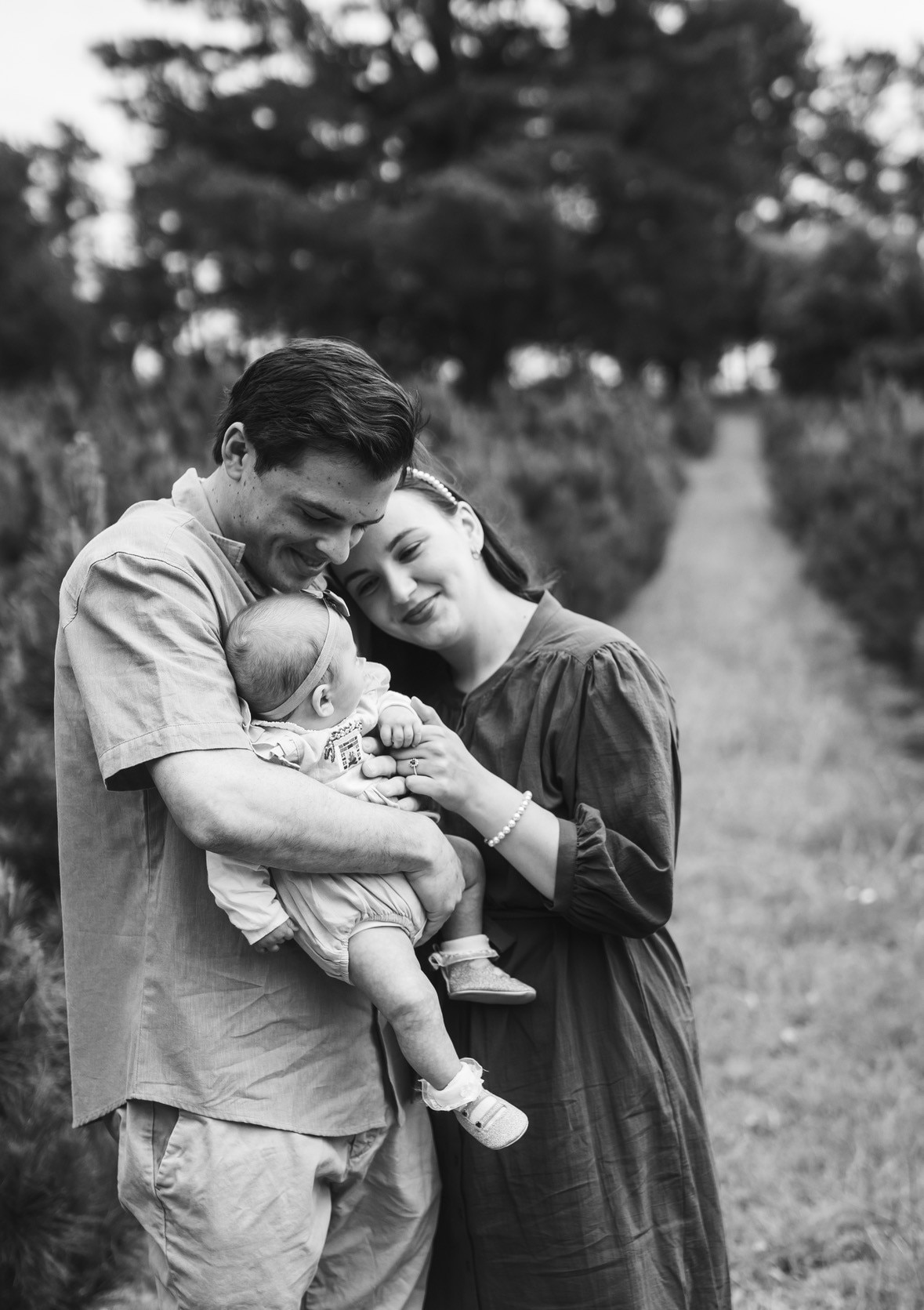 A woman and a man hold and smile lovingly at a baby.