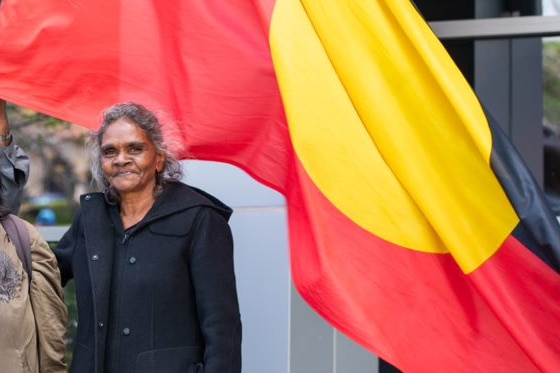 Maria smiles in front of the Australian Aboriginal flag 