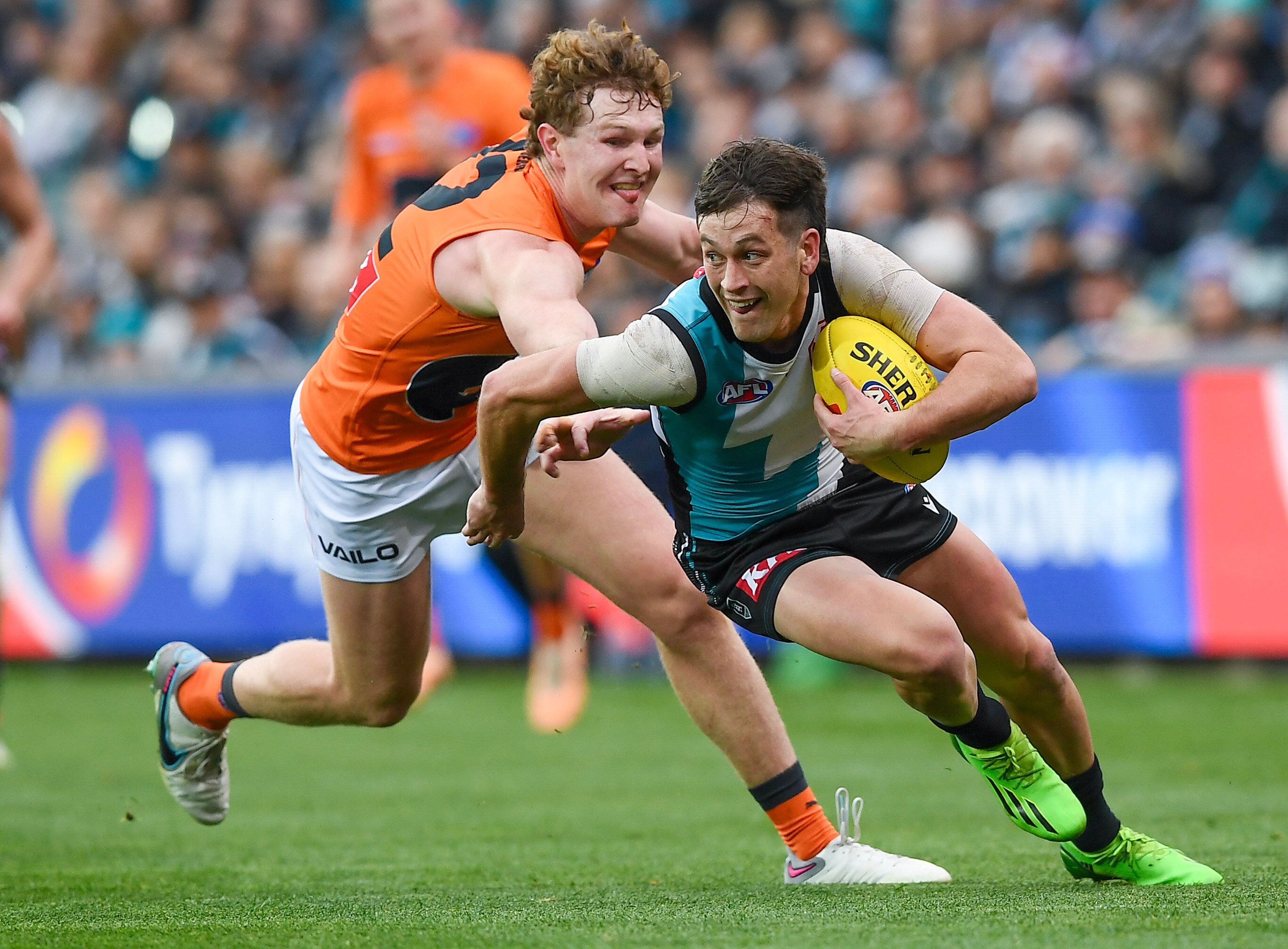 Zak Butters carries the ball as he runs away from Tom Green, who is trying to tackle him