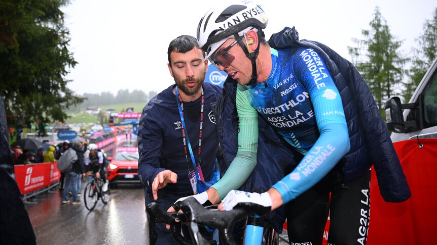 Ben O'Connor speaks to an official while on his bike