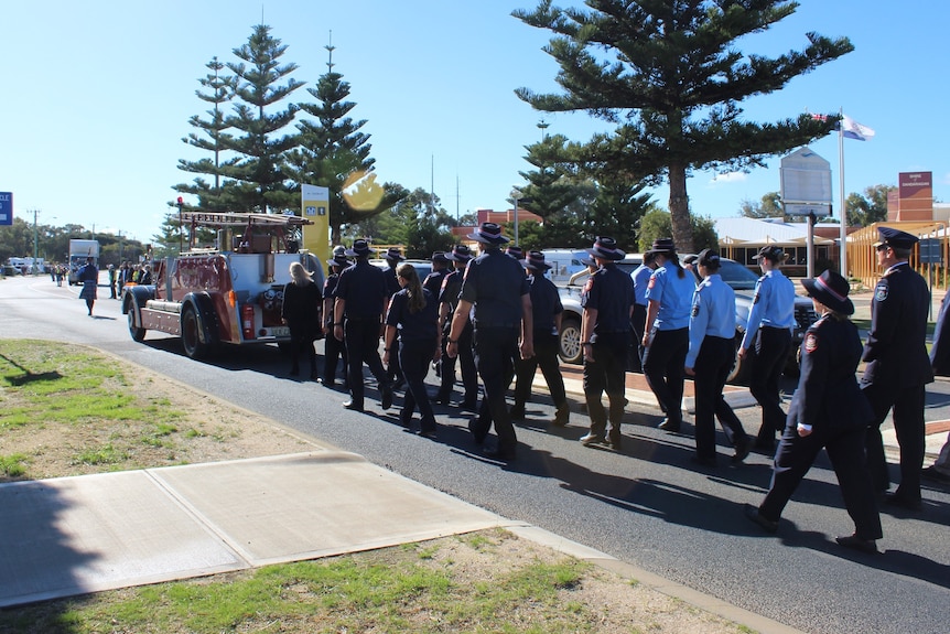 fire and rescue volunteers walk behind fire truck with community on street