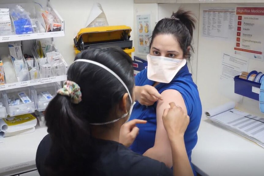 A nurses teaching another how to do a blood test 