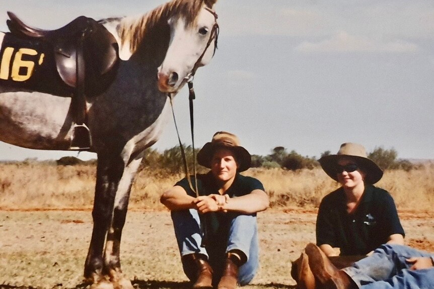 Lara Jensen and her brother Christian sitting on the ground next to a horse