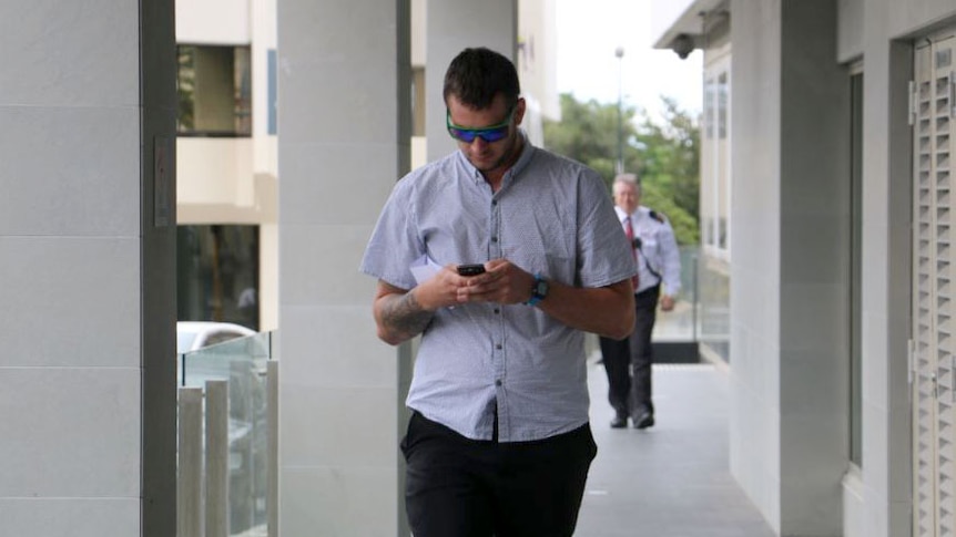 Volunteer firefighter Jordan Dean Ashford, with his head bent over his phone, outside Perth District Court.