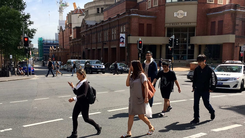 People texting while walking across the street at Haymarket, Sydney.