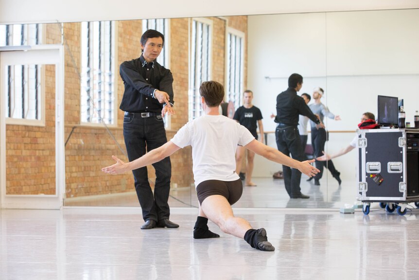Queensland Ballet Artistic Director Li Cunxin guiding a male dancer in rehearsal