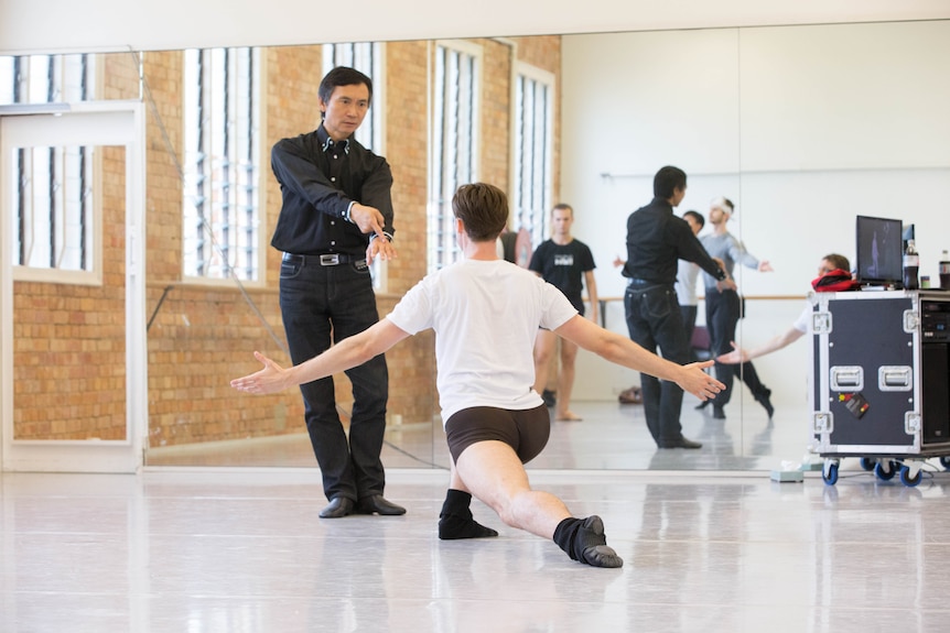 Queensland Ballet Artistic Director Li Cunxin guiding a male dancer in rehearsal