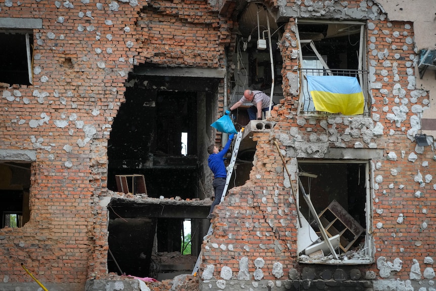 Residents take out their belongings from their house ruined by the Russian shelling