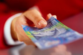 A hand with a ten dollar note (Thinkstock: Photodisc)