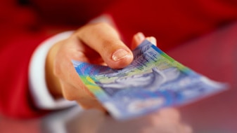 A hand with a ten dollar note (Thinkstock: Photodisc)