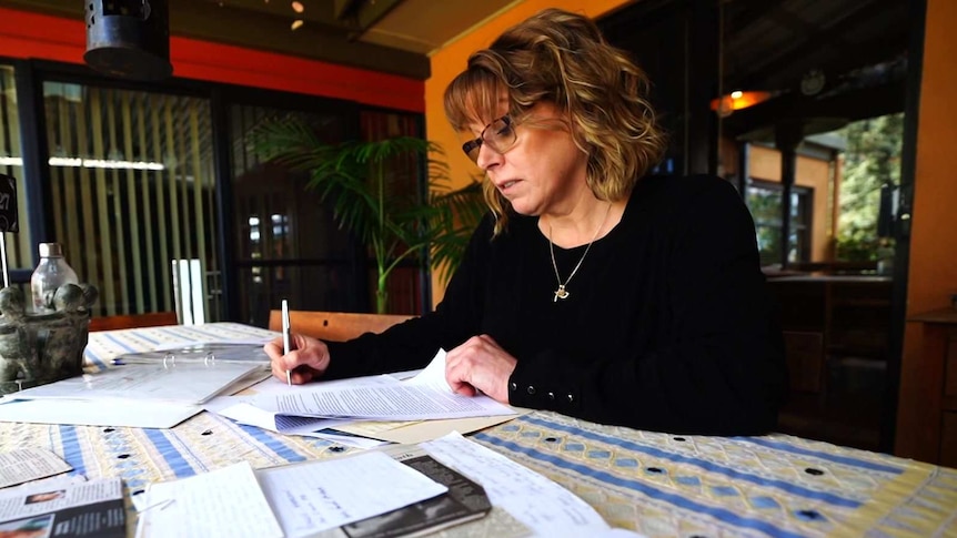 A woman with a pen looks at papers