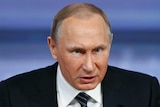 Russian President Vladimir Putin leans forward while speaking.