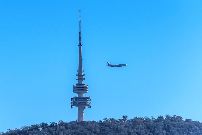 A 747 flies past Black Mountain Tower in Canberra.