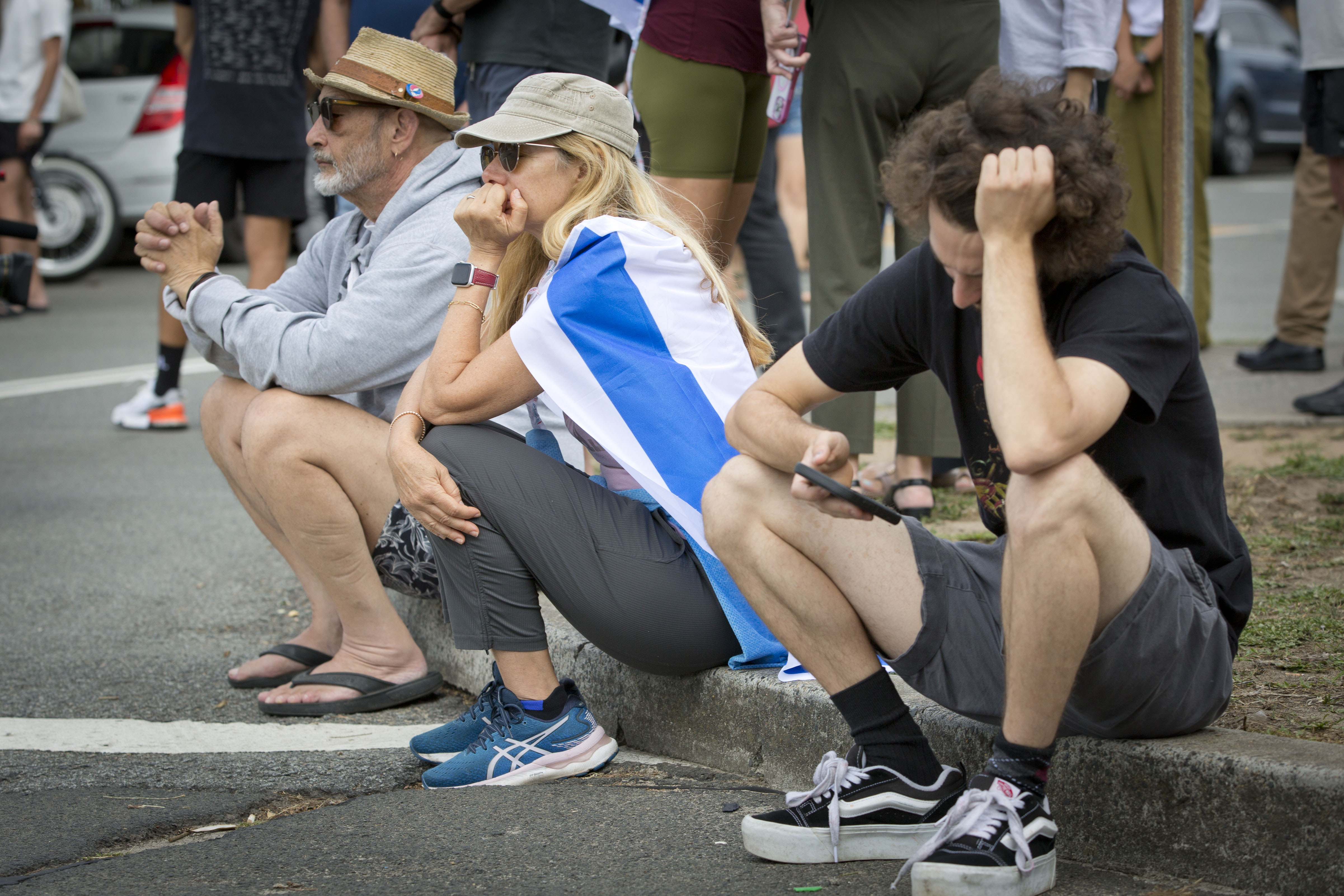 Uma mulher envolta na bandeira de Israel sentada na esquina