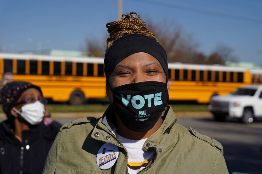 An African American woman in a mask with 'vote' written on it