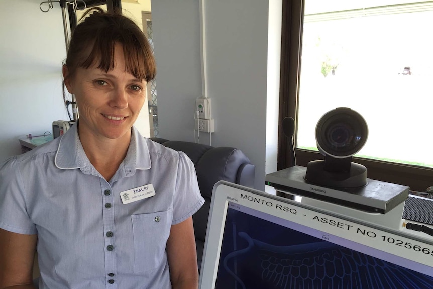 A nurse stands beside tele health equipment in a hospital room