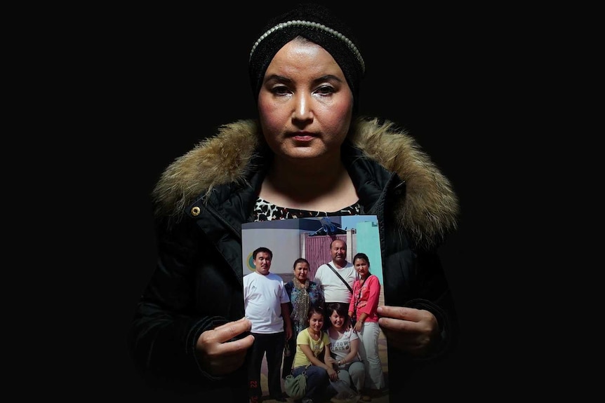 Fatimah Abdulghafur holds a family portrait against a black background.