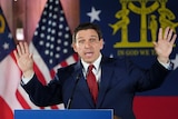 Ron DeSantis gesticulates in front of an American flag