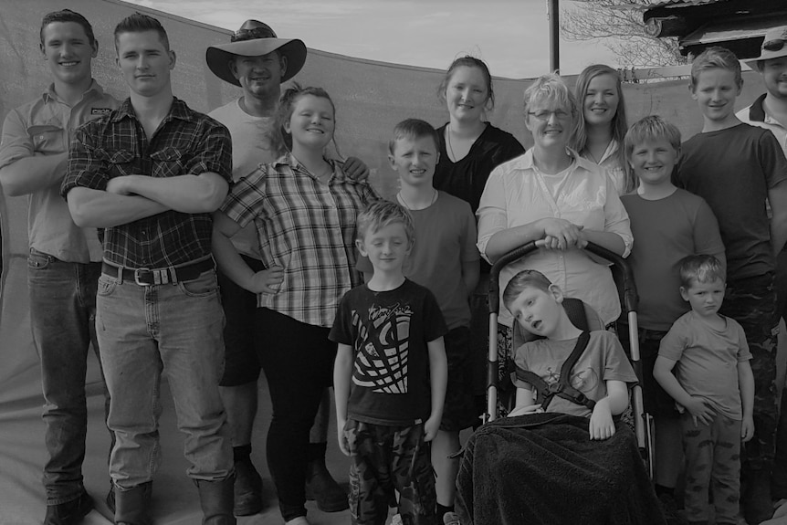 The Mitchell family, 15 people, stood side by side for a picture.