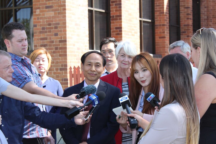 group of people facing media cameras and microphones