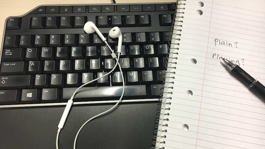 Ear phones on a keyboard with a book next to it.