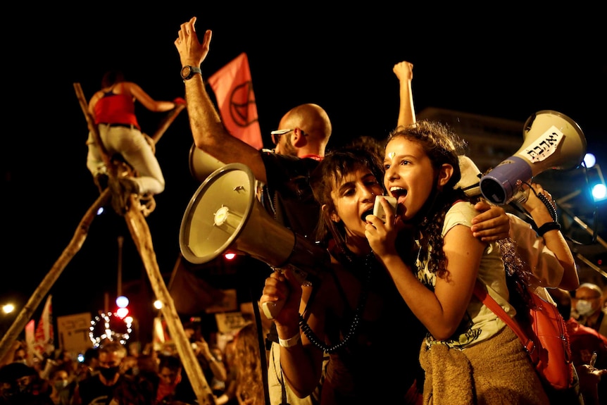 Two young Israeli women speaking in a loud speaker at a protest