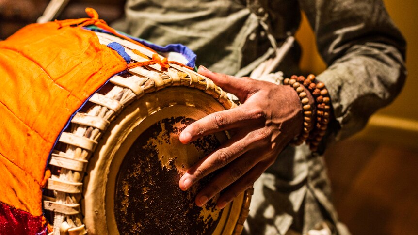 Close up of man playing the tabla for kirtan music session.