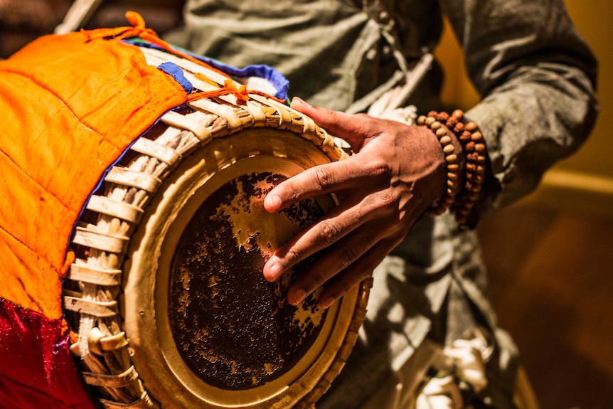 Close up of man playing the tabla for kirtan music session.