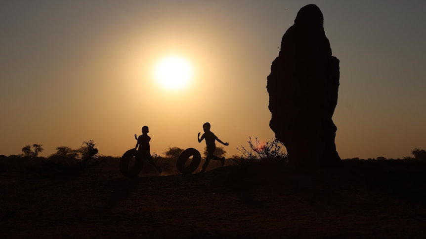 Two kids chasing tyres.