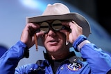 A man in a cowboy hat looks through space goggles