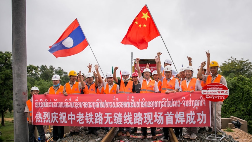 workers cheer after the first welding of seams for a BRI train running from China to Laos and beyond to the sea