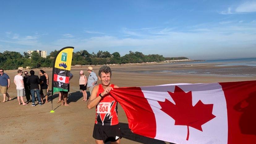 Athlete Nick Akers celebrates by flying the Canadian flag after breaking the 1 km world record for snowshoe running on sand