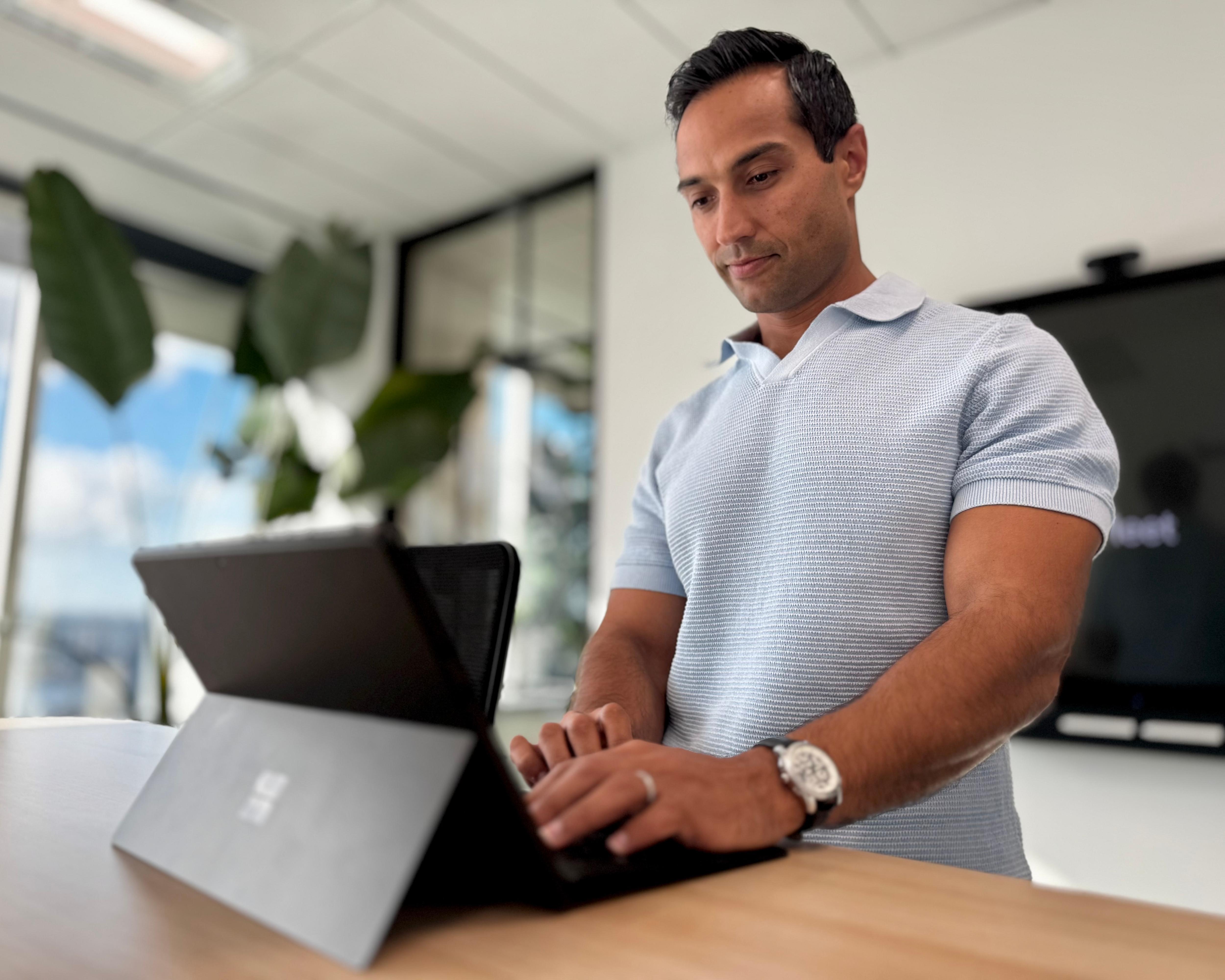 Man in office space works on laptop