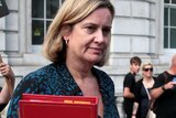 Amber Rudd walks among people with placard protesting against Brexit.