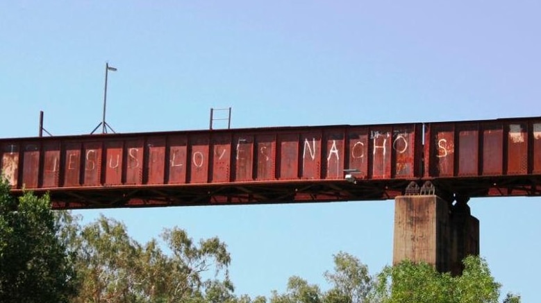 A picture of the Katherine Railway Bridge, with the slogan "Jesus loves nachos" graffitied on the side.