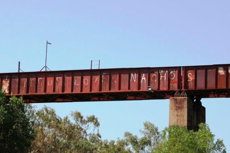 A picture of the Katherine Railway Bridge, with the slogan "Jesus loves nachos" graffitied on the side.