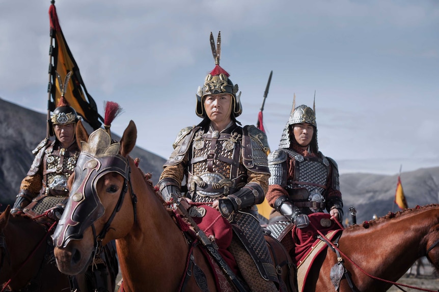 Donnie Yen in armour on a horse surrounded by other men in armour on horses in the movie Mulan