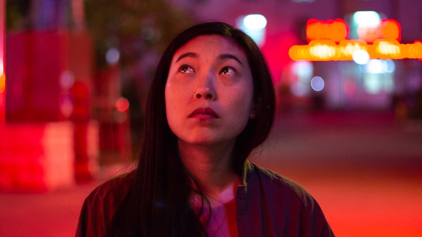 The main character of the film, a young Chinese woman, her eyes filled with tears, in a Chinese city.
