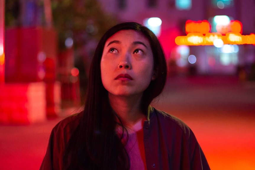 The main character of the film, a young Chinese woman, her eyes filled with tears, in a Chinese city.