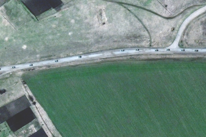 Спутниковый снимок автомобилей на дороге, окруженной зелеными пастбищными полями.