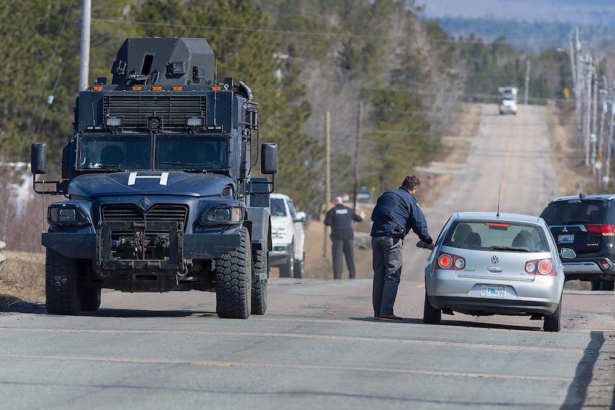 Police officers speak to drivers on a road