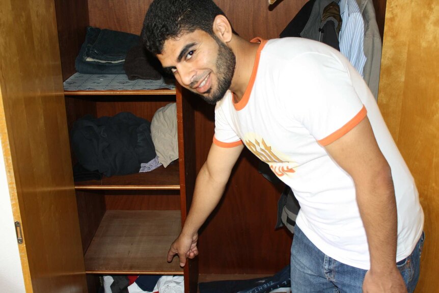 A Syrian refugee points to the place where he found hidden money in a donated wardrobe.