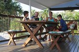 A photo of the Lovett family at their dinner table on the deck of their tropical home.