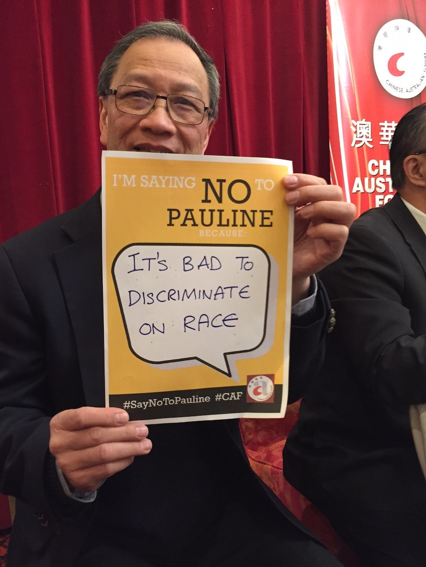 A man holds up a sign reading, "It's bad to discriminate on race."