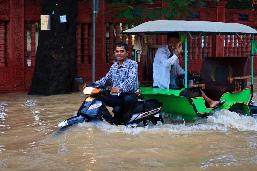 A man catches a ride in a tuk-tuk down a flooded street in Siem Reap in late September 2011.