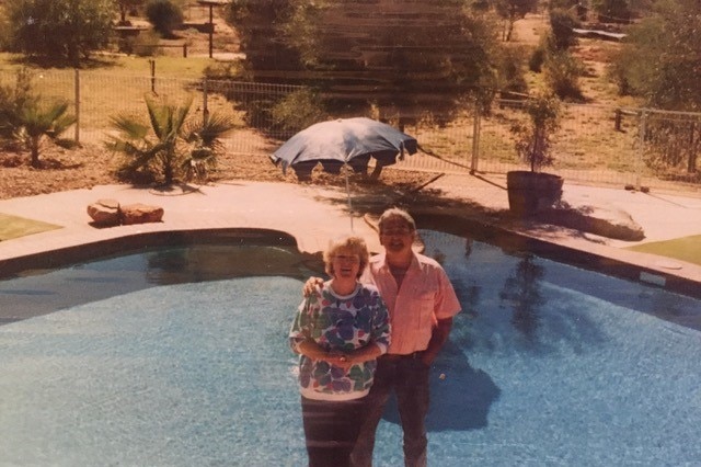 An older photo of a couple posing in front of an Australia-shaped pool.